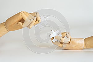 Business Solution Concept. Closeup of wooden hand model holding puzzle jigsaw on white background