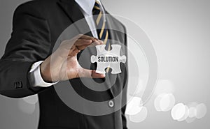 Business solution, strategy or success concept. Businessman is holding a jigsaw puzzle piece with the word â€˜SOLUTIONâ€™ on