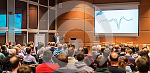 Business speaker giving a talk in conference hall.