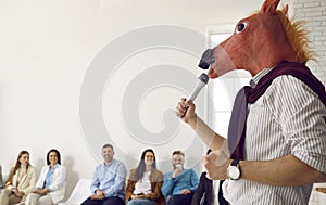 Business speaker in horse mask making funny presentation in front of happy audience