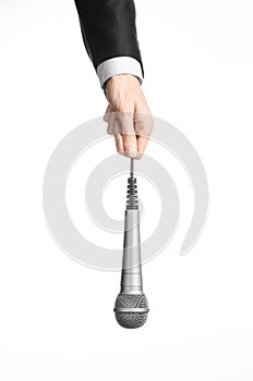 Business and speech topic: Man in black suit holding a gray microphone on an isolated white background in studio