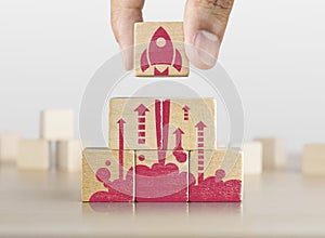 Business start up, start, new project or new idea concept. Wooden blocks with launching rocket graphic arranged in pyramid shape