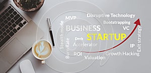 Business startup Concept. Words cloud of keywords.Computer laptop and coffee cup and pen on background top view