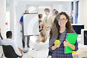 Business, startup and people concept - happy creative team with computer and folder in office