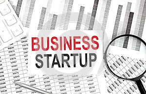 BUSINESS STARTUP text on paper with calculator,pen on graph background