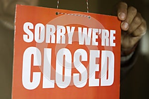 Business store owner turning closed sign at shop doorway