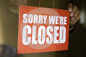 Business store owner turning closed sign at shop doorway