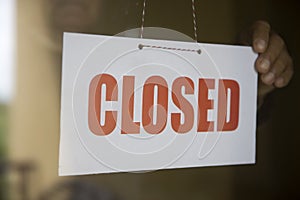 Business store owner turning closed sign at shop doorway