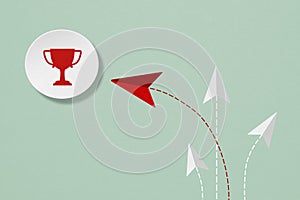 Business strategy concept, red trophy cup on grunge white paper cut with plane paper cut, red leading others  on grunge green