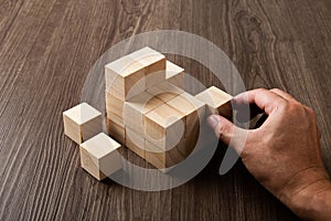 Business strategy conceptual idea. Human hand builds stack of wooden blocks