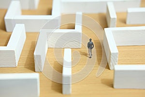 Business strategy conceptual photo - Miniature of businessman looking for solution on a labyrinth maze