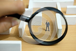 Business strategy conceptual photo - Miniature of businessman looking for solution on a labyrinth maze