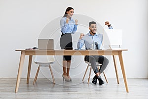 Workers using laptop celebrating success shaking fists screaming yes