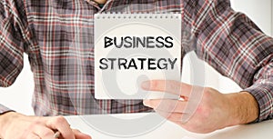 Business strategy text on notepad in hands businessman