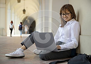 Business student on laptop, sitting in university halls photo