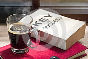 Business of success book and black coffee on wood near window