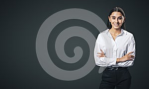 Business success concept with smiling woman folding her hands in white shirt and black trousers on abstract black blank