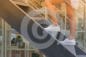 Business Success Concept : Woman is walking up black metal stairs outside the buildings.