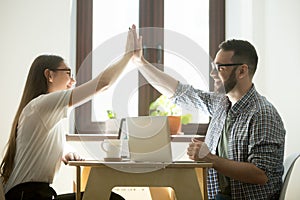 Business success: two happy employees making high five in office