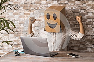 Business and success working with laptop. People with carton box smile on head celebrate and exult in front of a computer. New photo