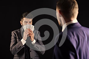 Business succsses. Man with beard on calm face sniffing money, smell of profit. Meeting of reputable businessmen, black photo