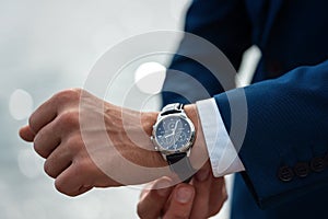 Business suit checking a wrist watch on his hand on background  sea