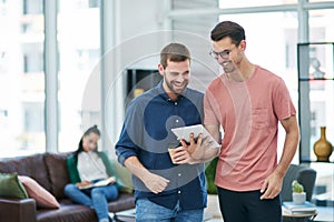 Business survival needs a strong online presence. two young businessmen using a digital tablet together in a modern