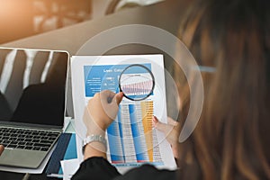 Business team analysing financial data with a magnifying glass