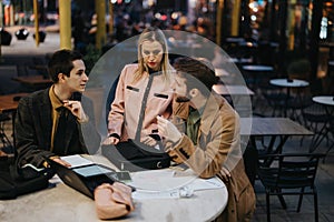 Business team analyzing project details during an outdoor meeting at a cafe at dusk