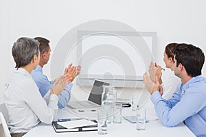 Business team applauding and looking at white screen