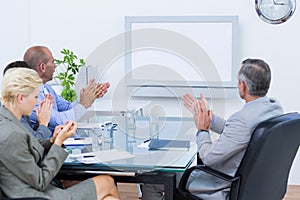 Business team applauding and looking at white screen