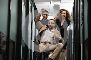 Business team celebrating in office. Successful entrepreneurs and business people achieving goals. Boss sitting on chair and ride