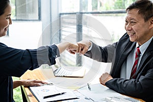 Business team is checking business document together and making a fist-bump after mission complete