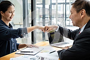 Business team is checking business document together and making a fist-bump after mission complete