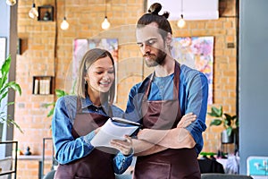 Business team, confident colleagues young man and woman in aprons with notebook