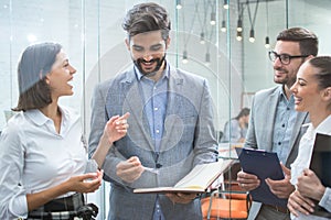 Business team discussing business documents, standing in the office lobby.