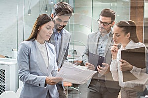 Business team discussing business documents, standing in the office lobby