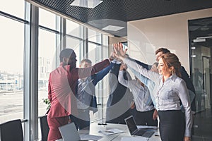 Business team giving a high fives gesture as they laugh and cheer their success