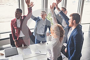 Business team giving a high fives gesture as they laugh and cheer their success