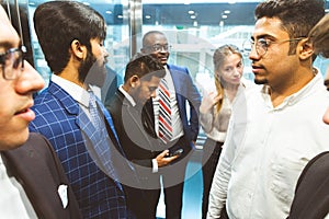 Business team group going on elevator. Business people in a large glass elevator in a modern office. Corporate