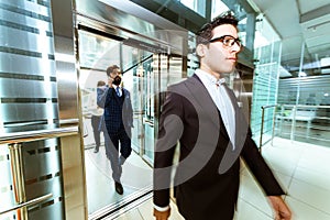 Business team group going on elevator. Business people in a large glass elevator in a modern office. Corporate