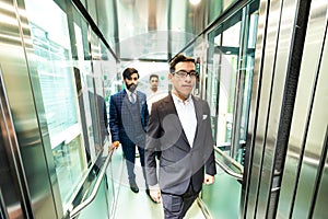 Business team group going on elevator. Business people in a large glass elevator in a modern office. Corporate