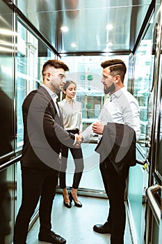 Business team group going on elevator. Business people in a large glass elevator in a modern office. Corporate