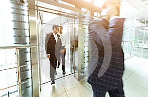 Business team group going on elevator. Business people in a large glass elevator in a modern office. Corporate