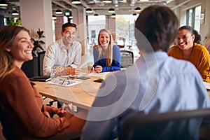 Business Team Having Meeting Sitting Around Table In Modern Open Plan Office