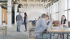 Business team holds a meeting in the office in a loft style. A young woman gets up from her workplace, walks to the