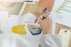 Business team image of male hand pointing at business document during discussion at meeting and using pen with financial diagram