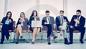 Business team with laptop and smartphone sitting on the sofa in