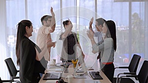 The business team leader calls the team members to join hands to show the team`s success