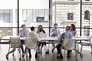 Business team look to manager at meeting in open plan office